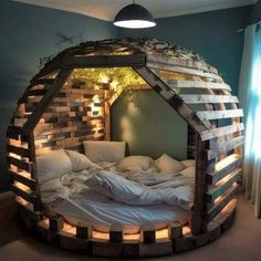 a bed made out of wooden pallets with lights on the side and pillows in it