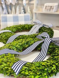 a wreath with blue and white striped ribbon on it sitting on top of a table