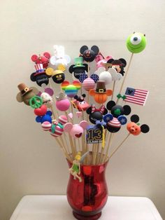 a red vase filled with lots of mickey mouse pins