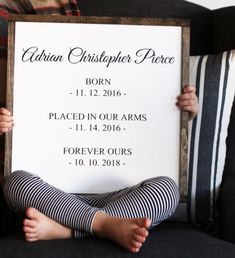 a person sitting on a couch with a sign in front of them that says nathan christopher pierce born 11 - 12 - 2016 placed