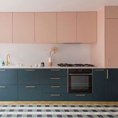 a kitchen with an oven, sink and cabinets in pastel pink and navy blue