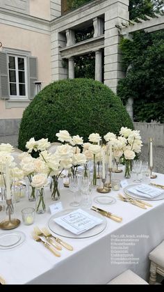 the table is set with white flowers and gold place settings for an elegant wedding reception