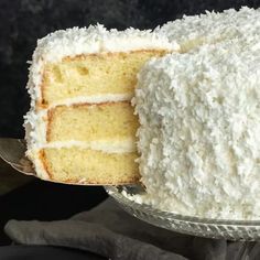 a close up of a cake with white frosting on a glass plate and one slice being taken out