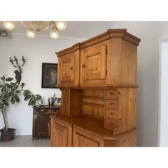 a large wooden cabinet sitting in the corner of a room next to a potted plant