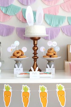 a table topped with donuts and cakes covered in paper bunnies next to other desserts