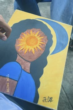 a person is holding up a painting with the sun on it's face and head