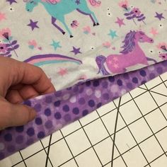 someone is cutting out the fabric for a unicorn print skirt with purple polka dots and stars