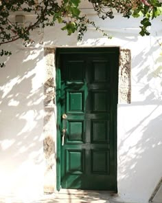 a green door is open in front of a white building