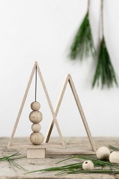 two wooden pyramids sitting on top of a table next to pine cones and needles