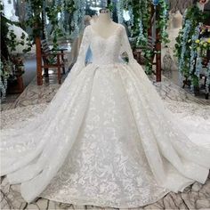 a white wedding dress on display in a room full of flowers and greenery,