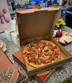 a pizza in a box sitting on top of a counter next to boxes of cheese and pepperoni