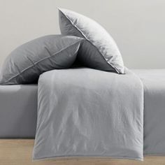 a bed with two pillows on top of it next to a wooden floor and wall