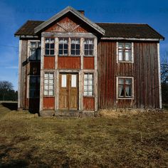 an old wooden house sitting on top of a grass covered field