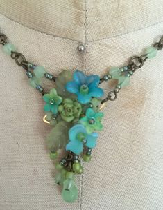 a close up of a necklace with flowers and beads hanging from it's center