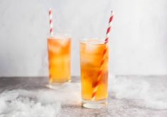 two glasses filled with orange liquid and straws