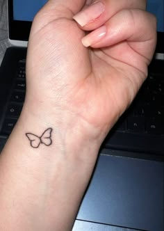 a woman's wrist with a small butterfly tattoo on the left side of her arm