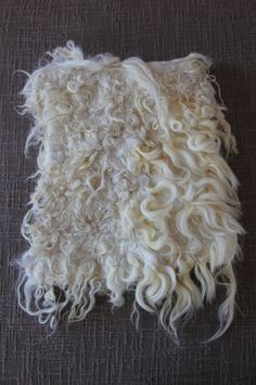 a pile of white hair on top of a gray floor next to a black wall