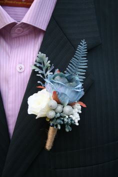 a boutonniere with white flowers and greenery is worn on a man's suit