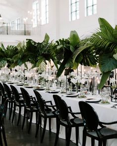 a long table is set up with black chairs and white linens for an elegant dinner