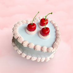 two cherries sitting on top of a heart shaped cake