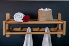 two towels are sitting on a wooden shelf next to a bag and towel rack in a bathroom