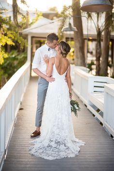 a bride and groom kissing on a bridge