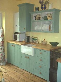 a kitchen with blue cabinets and wooden floors is pictured in this image, there is a dog sitting on the floor next to the sink