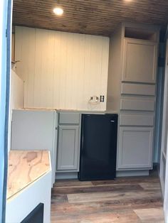 an empty kitchen with wood floors and white cabinets, black refrigerator and dishwasher