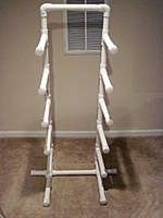 a white rack that is on the floor in front of a window with shutters