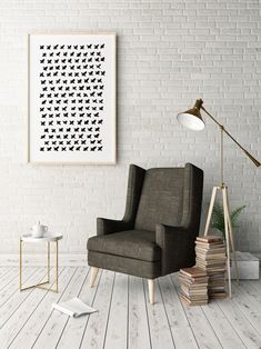 a chair in front of a white brick wall with a lamp and books on the floor