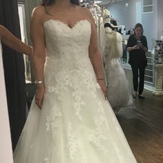 a woman standing in front of a mirror wearing a wedding dress