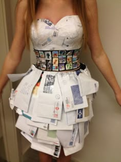 a woman in a white dress made out of newspaper strips and other paper items is posing for the camera