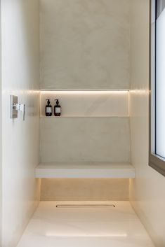 an empty white bathroom with two bottles on the shelf