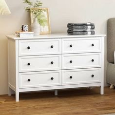 a white dresser sitting next to a gray chair