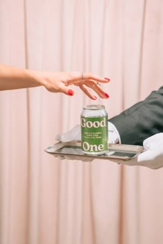 a person holding a tray with a can on it and another hand reaching out to grab something