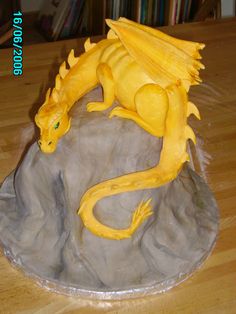 a yellow dragon figurine sitting on top of a rock in the middle of a wooden table