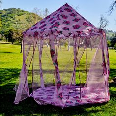 a pink tent sitting on top of a lush green field