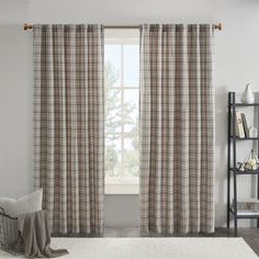 a living room filled with furniture and a window covered in plaid drapes next to a white rug