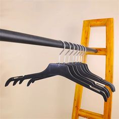 a bunch of black clothes hangers on a wooden ladder