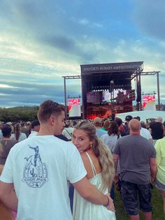 two people are standing in front of an outdoor stage at a music festival or concert