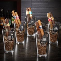 six shot glasses filled with cigars on top of a table