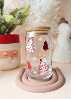 a glass jar sitting on top of a table next to a potted christmas tree