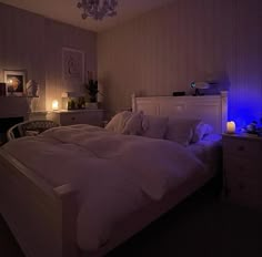 a white bed sitting in a bedroom next to a night stand with candles on it