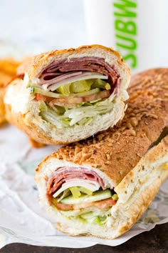 two sandwiches cut in half sitting on top of paper wrappers next to french fries