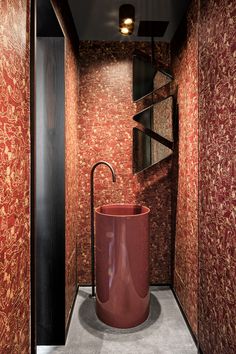 the bathroom is decorated with red and gold wallpaper, along with a round vessel sink