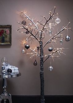 a christmas tree with ornaments and lights on it in front of a wall decorated with an ornament