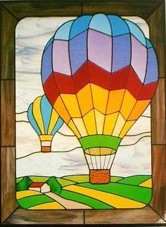 a colorful hot air balloon is in the sky above a green field and farm land