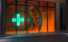 an orange and green hospital sign in front of a glass building with the words save on it