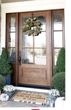 the front door is decorated with wreaths and potted plants