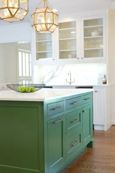 a kitchen with green cabinets and gold chandelier hanging from the light fixture over the island